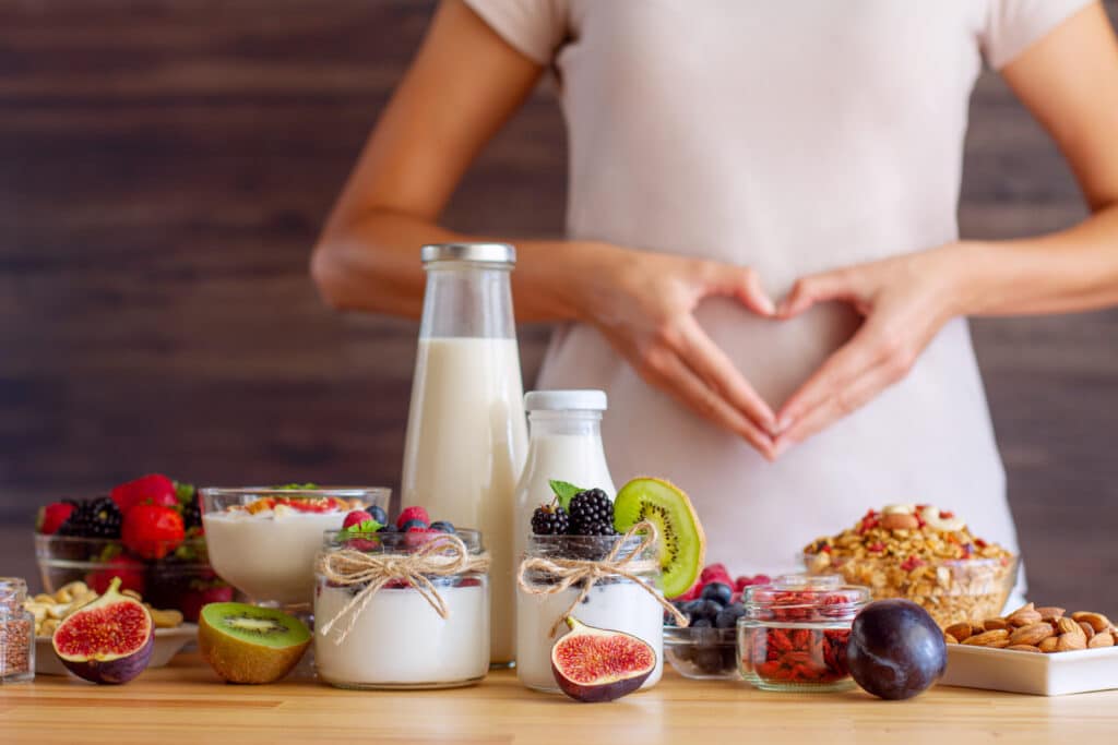 Healthy breakfast of yogurt, fruit, and nuts with hands in a heart shape, illustrating how targeted nutrition can improve gut microbiome health.