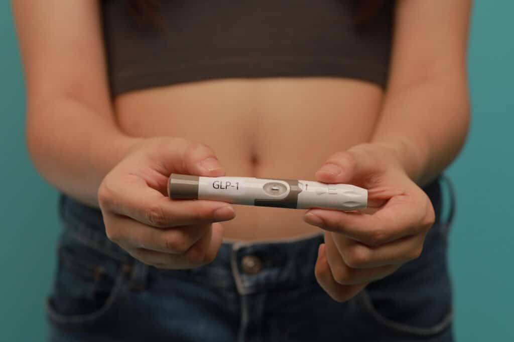 GLP 1 injection pen held by woman for medical weight management